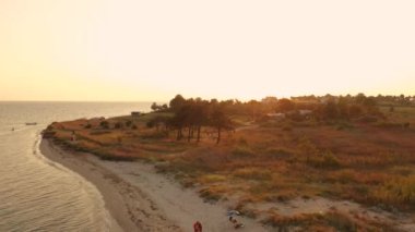 Gün batımı kum sahil denizi üzerindeki 4K hava manzarası. Yunanistan sahil köyü Trakya körfezi küçük evleri 