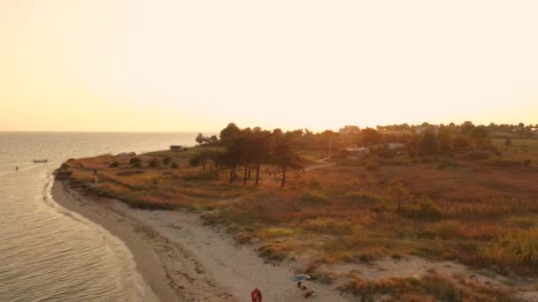 日没の砂浜の海の上に4kの空中トップビュー。ギリシャの海辺の村の小さな家ベイトラキアの海 — ストック動画