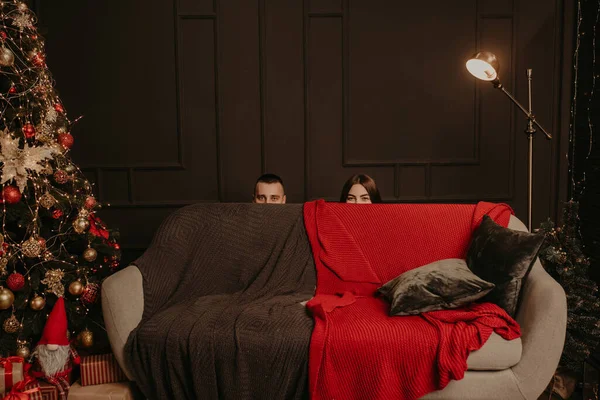 Un uomo e una donna nascosti dietro il divano. teste di un uomo e una donna sporgono da dietro il divano — Foto Stock