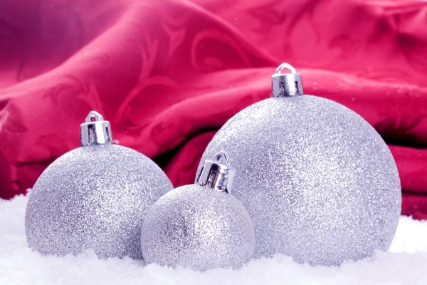 Julgranskulor med snö och röd bakgrund — Stockfoto