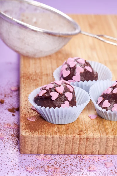 Dark chocolate pralines with pink hearts — Stock Photo, Image
