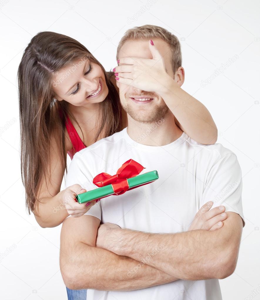 young woman giving a surprise present to her boyfriend