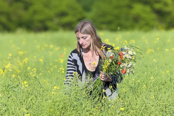 Vrouw wilde bloemen plukken op de weide — Stockfoto