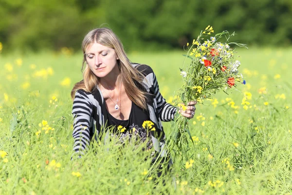 Mujer recogiendo flores silvestres en el prado — Foto de Stock