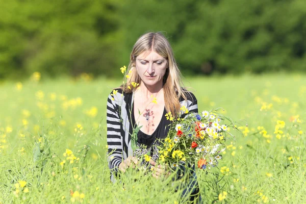 Mujer recogiendo flores silvestres en el prado — Foto de Stock