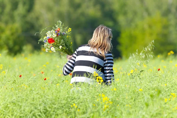 Mujer recogiendo flores silvestres en el prado — Foto de Stock