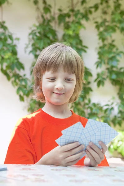 Menino com cabelos loiros jogando cartas — Fotografia de Stock