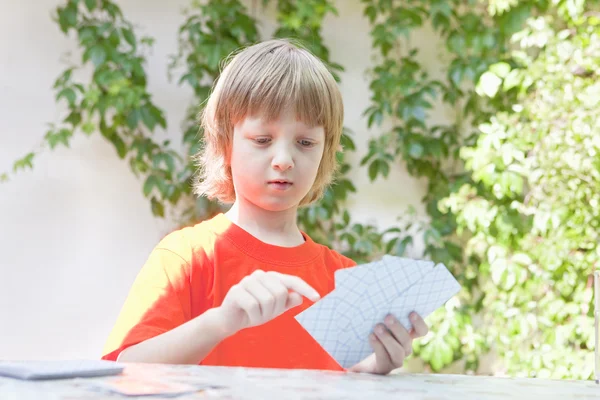 Menino com cabelos loiros jogando cartas — Fotografia de Stock