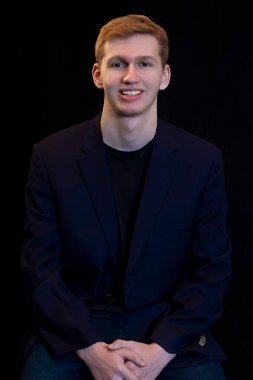 Yakından çekilmiş, kumral saçlı, siyah bir spor ceket giyen ve kapüşonlu giyen genç bir adamın portreleri.