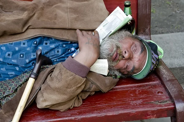Homem sem-teto dormindo em um banco — Fotografia de Stock