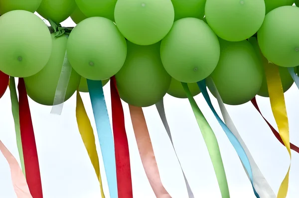 Zielone balony z rozwijającymi się kolorowymi wstążkami — Zdjęcie stockowe