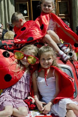 Children dressed as ladybugs sitting on retro car clipart