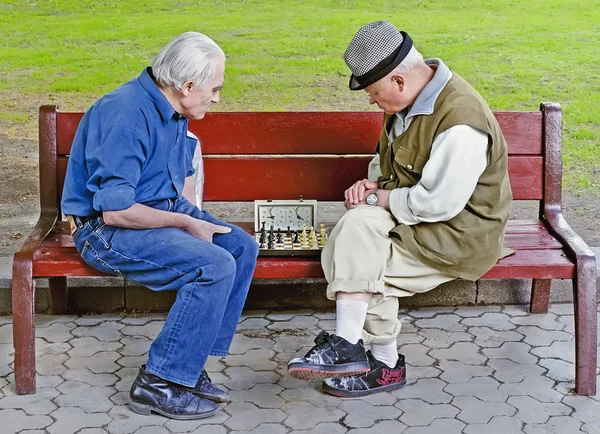 Ältere Menschen spielen Schach auf einer Bank — Stockfoto