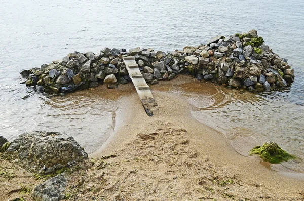 Bridge on a pile of rocks in the sea — Stock Photo, Image