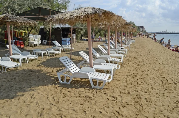 Liegestühle und Sonnenschirme aus Schilf am Strand — Stockfoto