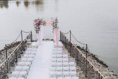 Sonbahar düğünü, iskelede suyun kenarında pembe aylak ayini.