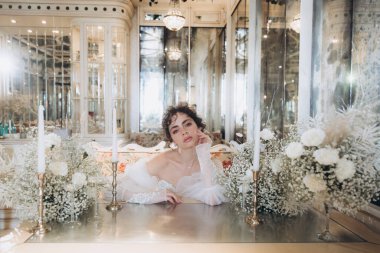 Güzel kıvırcık saçlı gelin lüks bir gelinlik içinde düğün dekorlu bir restoranda