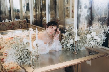 Güzel kıvırcık saçlı gelin lüks bir gelinlik içinde düğün dekorlu bir restoranda