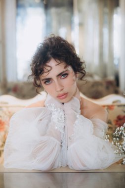 Güzel kıvırcık saçlı gelin lüks bir gelinlik içinde düğün dekorlu bir restoranda