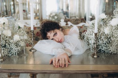 Güzel kıvırcık saçlı gelin lüks bir gelinlik içinde düğün dekorlu bir restoranda