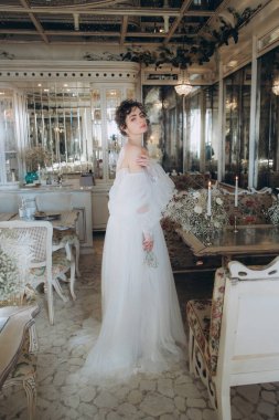 Güzel kıvırcık saçlı gelin lüks bir gelinlik içinde düğün dekorlu bir restoranda