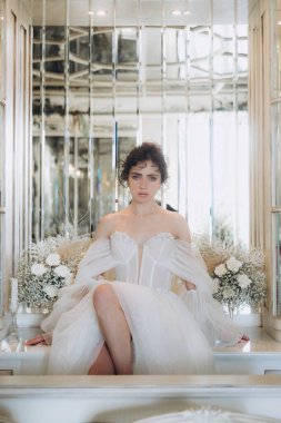 Güzel kıvırcık saçlı gelin lüks bir gelinlik içinde düğün dekorlu bir restoranda