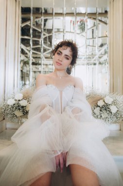 Güzel kıvırcık saçlı gelin lüks bir gelinlik içinde düğün dekorlu bir restoranda