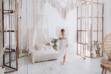 Gelinin kırsal tarzda bir sabah, beyaz bornoz ve beyaz bir buket içinde yatağın ve banyonun yanında bir fotoğraf stüdyosunun, bir otelin penceresinin yanında