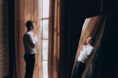 Şık bir damat sabahı, siyah bir takım elbise ve kravatla, oteldeki hazırlıkları, bir fotoğraf stüdyosunda, düğmeler ve ceketler, portreler.