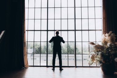 Şık bir damat sabahı, siyah bir takım elbise ve kravatla, oteldeki hazırlıkları, bir fotoğraf stüdyosunda, düğmeler ve ceketler, portreler.