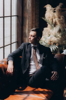 Şık bir damat sabahı, siyah bir takım elbise ve kravatla, oteldeki hazırlıkları, bir fotoğraf stüdyosunda, düğmeler ve ceketler, portreler.