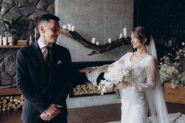 Siyah takım elbiseli damadın ilk buluşması ve siyah arka planda bir fotoğraf stüdyosunun, otelin içinde beyaz gelinlik içinde bir buket.