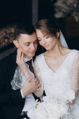 Siyah takım elbiseli damadın ilk buluşması ve siyah arka planda bir fotoğraf stüdyosunun, otelin içinde beyaz gelinlik içinde bir buket.