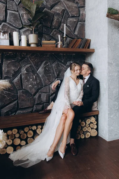 Siyah takım elbiseli damadın ilk buluşması ve siyah arka planda bir fotoğraf stüdyosunun, otelin içinde beyaz gelinlik içinde bir buket.