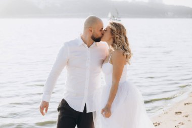 Güzel bir çiftin gün batımında düğün fotoğrafları, beyaz elbiseli gelin, beyaz gömlekli ve siyah pantolonlu damat.