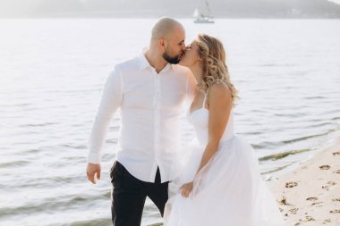 Güzel bir çiftin gün batımında düğün fotoğrafları, beyaz elbiseli gelin, beyaz gömlekli ve siyah pantolonlu damat.
