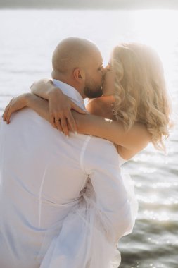 Güzel bir çiftin gün batımında düğün fotoğrafları, beyaz elbiseli gelin, beyaz gömlekli ve siyah pantolonlu damat.