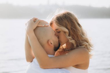 Güzel bir çiftin gün batımında düğün fotoğrafları, beyaz elbiseli gelin, beyaz gömlekli ve siyah pantolonlu damat.