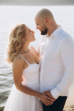 Wedding photosession at sunset of a beautiful couple, the bride in a white dress, and the groom in a white shirt and black trousers