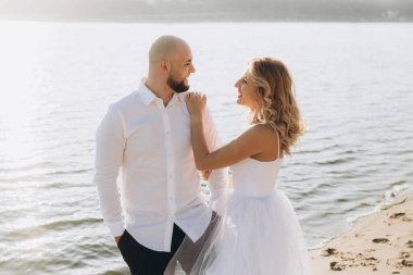 Wedding photosession at sunset of a beautiful couple, the bride in a white dress, and the groom in a white shirt and black trousers