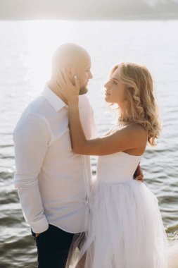 Güzel bir çiftin gün batımında düğün fotoğrafları, beyaz elbiseli gelin, beyaz gömlekli ve siyah pantolonlu damat.