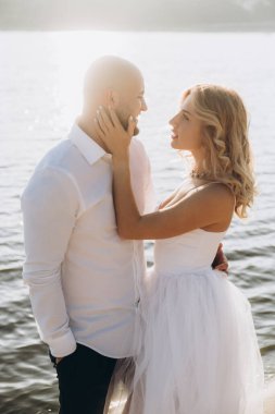Güzel bir çiftin gün batımında düğün fotoğrafları, beyaz elbiseli gelin, beyaz gömlekli ve siyah pantolonlu damat.