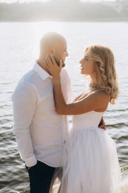 Wedding photosession at sunset of a beautiful couple, the bride in a white dress, and the groom in a white shirt and black trousers