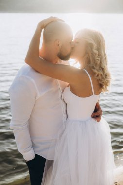 Güzel bir çiftin gün batımında düğün fotoğrafları, beyaz elbiseli gelin, beyaz gömlekli ve siyah pantolonlu damat.