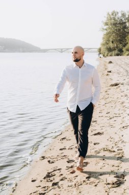 Güzel bir çiftin gün batımında düğün fotoğrafları, beyaz elbiseli gelin, beyaz gömlekli ve siyah pantolonlu damat.