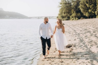 Güzel bir çiftin gün batımında düğün fotoğrafları, beyaz elbiseli gelin, beyaz gömlekli ve siyah pantolonlu damat.