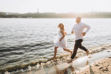 Güzel bir çiftin gün batımında düğün fotoğrafları, beyaz elbiseli gelin, beyaz gömlekli ve siyah pantolonlu damat.