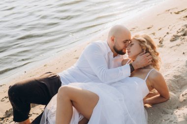 Güzel bir çiftin gün batımında düğün fotoğrafları, beyaz elbiseli gelin, beyaz gömlekli ve siyah pantolonlu damat.