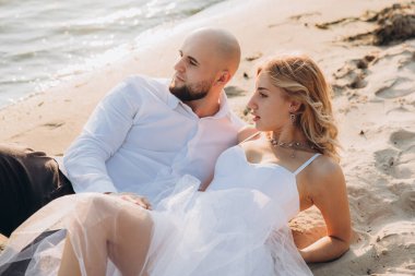 Güzel bir çiftin gün batımında düğün fotoğrafları, beyaz elbiseli gelin, beyaz gömlekli ve siyah pantolonlu damat.