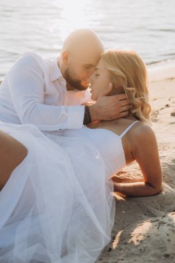 Güzel bir çiftin gün batımında düğün fotoğrafları, beyaz elbiseli gelin, beyaz gömlekli ve siyah pantolonlu damat.